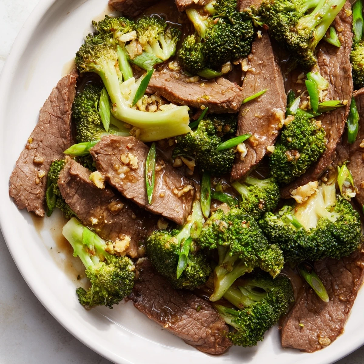 Freshly cooked Keto Friendly Beef and Broccoli Stir Fry served on a white plate, garnished with sesame seeds and scallions.