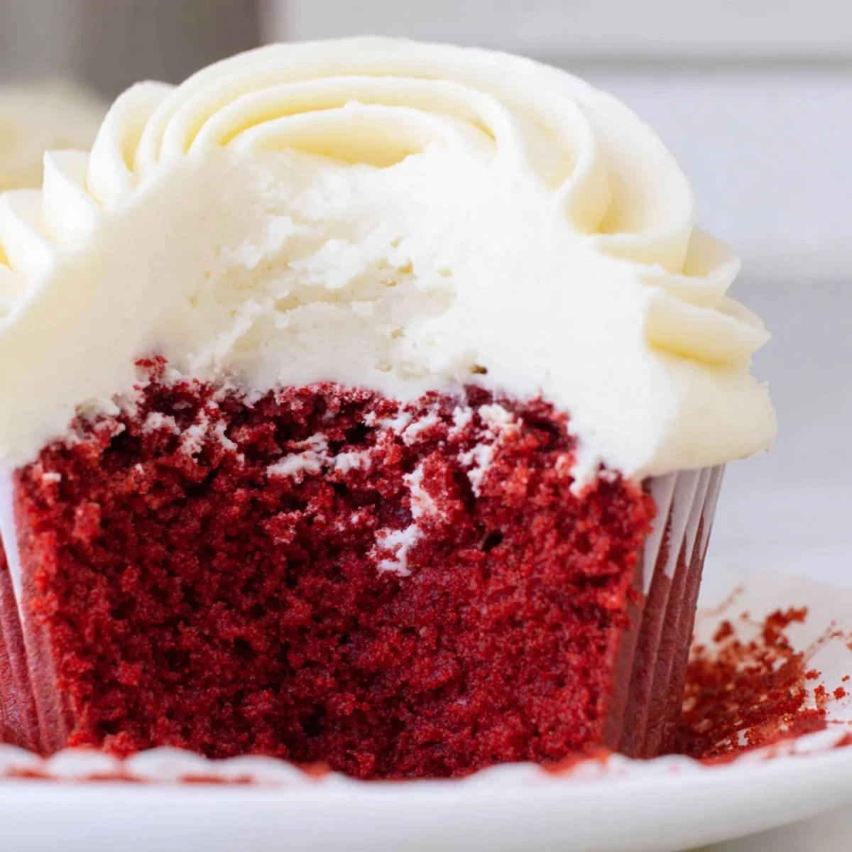 Generously swirled Red Velvet Cupcakes with cream cheese frosting, topped with chocolate shavings and served on a marble board.