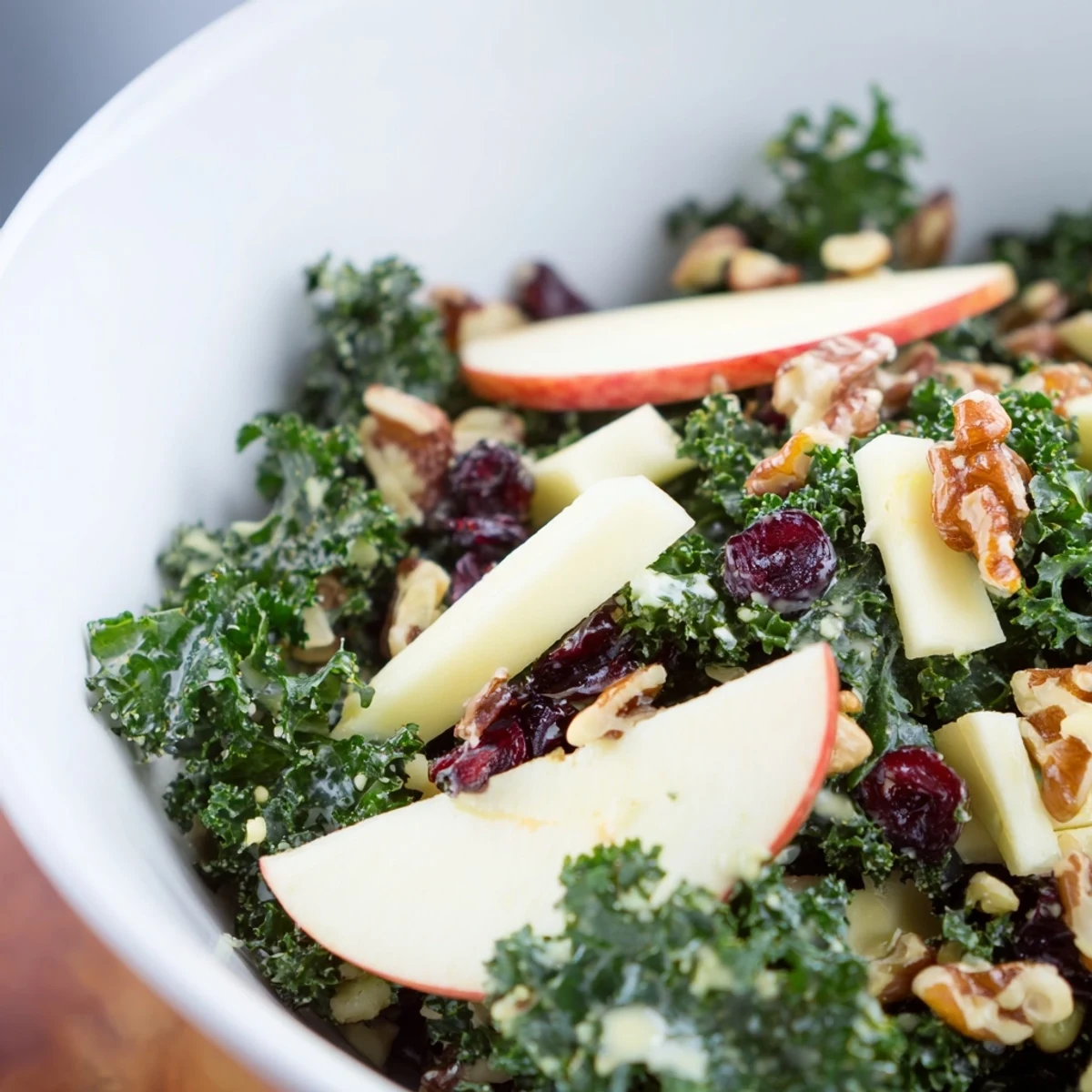 Festive winter kale salad with apple and sharp cheddar, served with pumpkin seeds and dried cranberries.