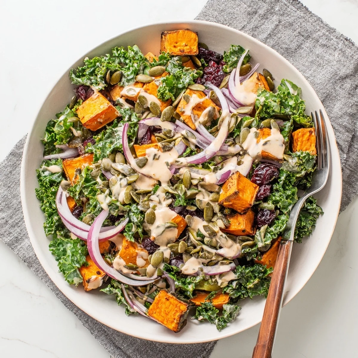 A close-up of the Kale and Sweet Potato Salad with Tahini Dressing, highlighting the golden sweet potatoes and crunchy toasted pumpkin seeds.