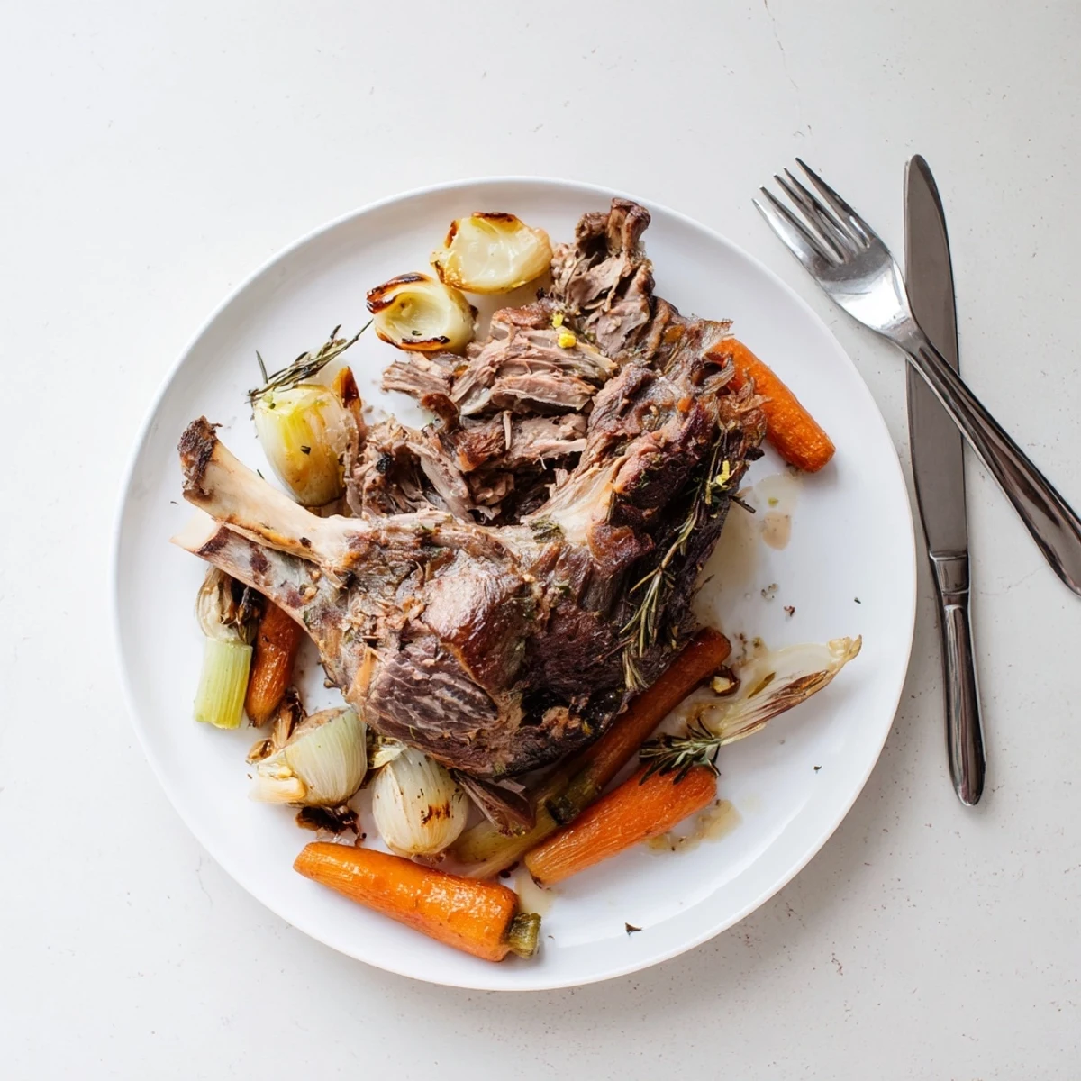 Golden-brown Slow Cooked Lamb Shoulder with Garlic Herbs resting on a bed of caramelized onions and carrots, garnished with fresh rosemary.