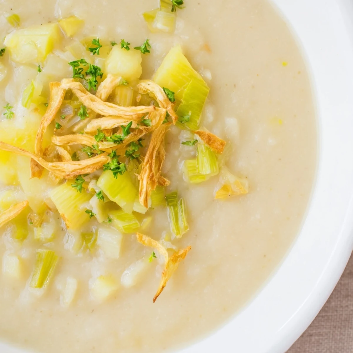Creamy Irish Potato Leek Soup topped with golden, crispy leeks served in a rustic bowl.