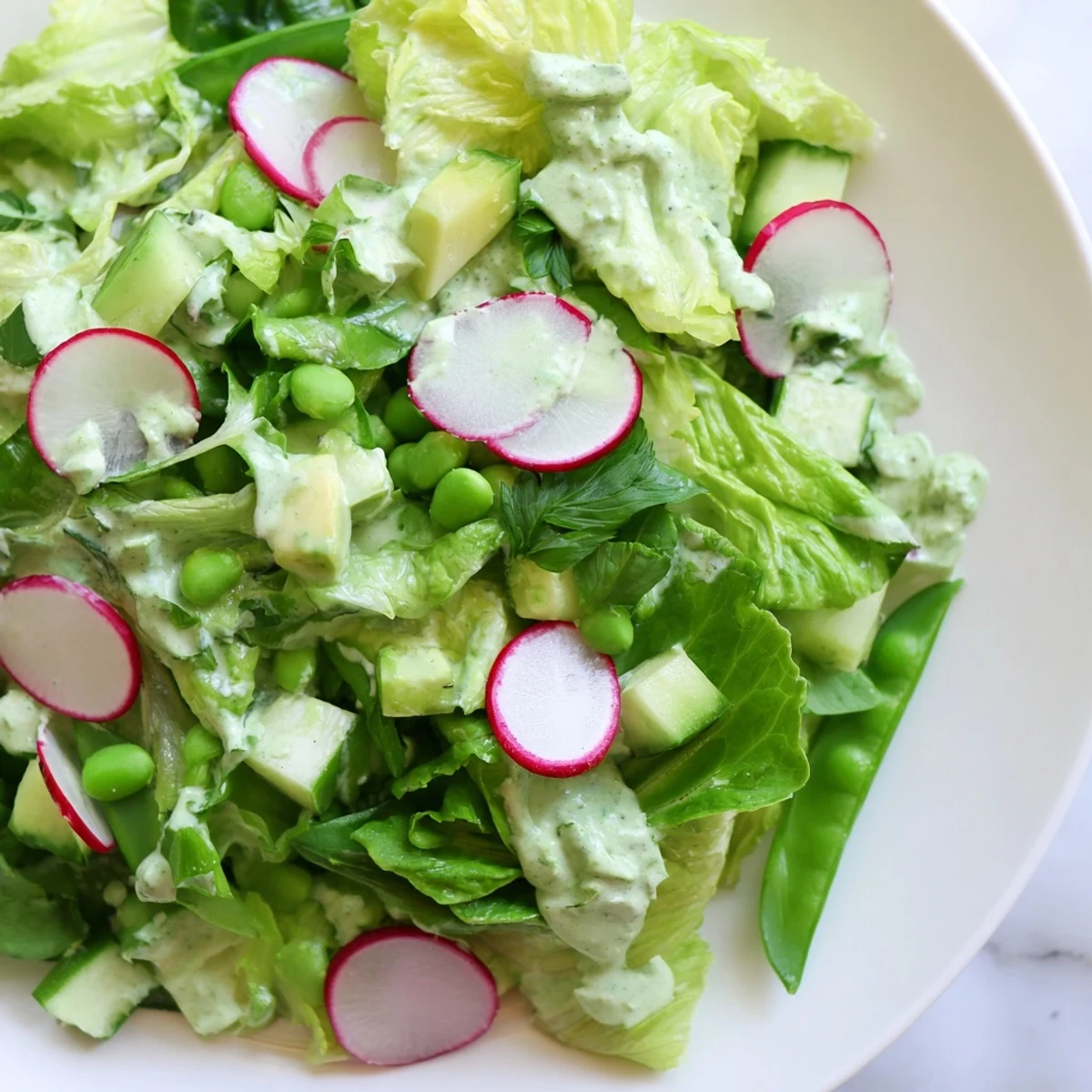 This fresh Green Goddess Salad with Avocado Dressing features snap peas, radishes, and herbs, perfect for a healthy lunch or light dinner.