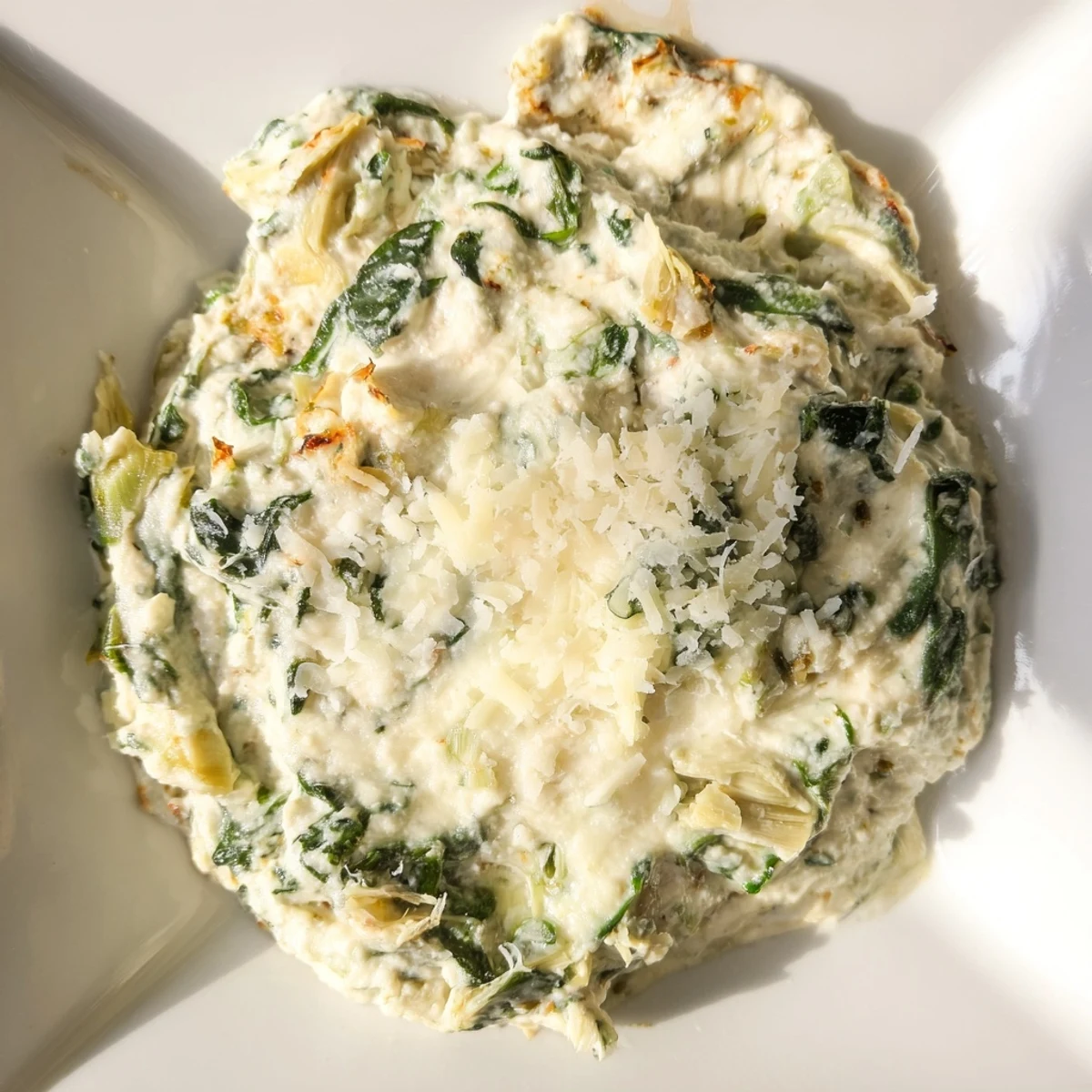 A bubbling, golden-brown Creamy Spinach and Artichoke Dip is scooped onto a crusty baguette slice.