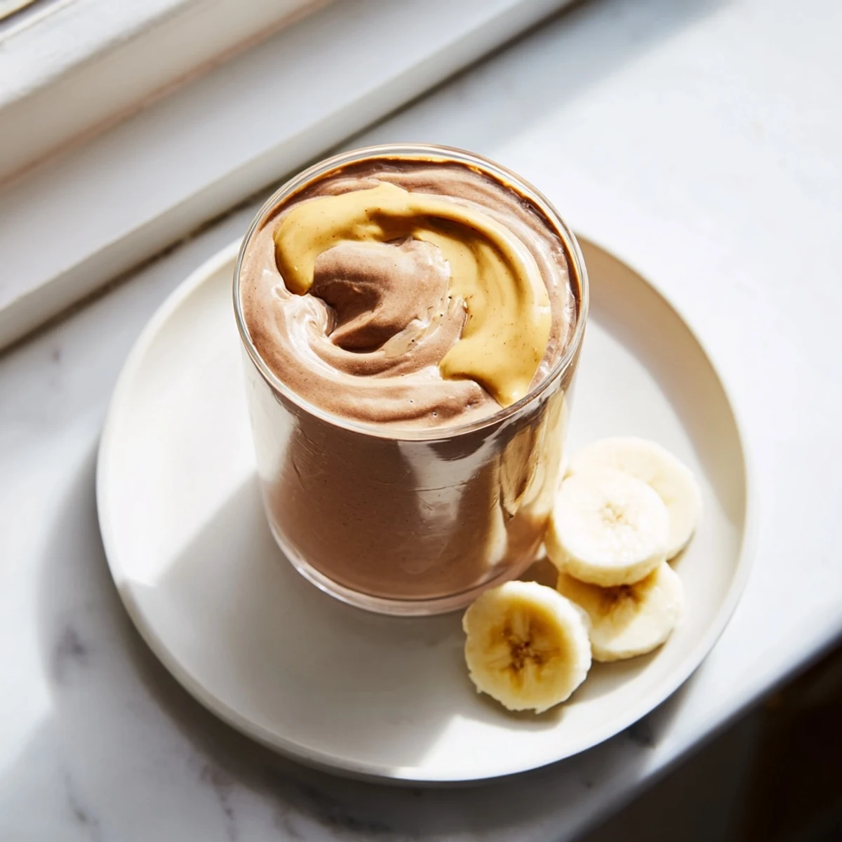 Thick Chocolate Peanut Butter Smoothie with Banana blended with ice, served with a straw, perfect for breakfast or an afternoon snack.