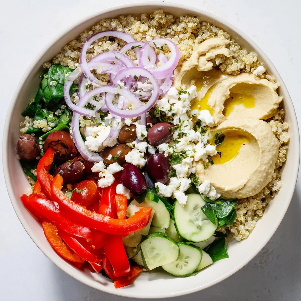 A vibrant Mediterranean Quinoa Bowl with Hummus topped with fresh tomatoes and cucumber on a rustic table.