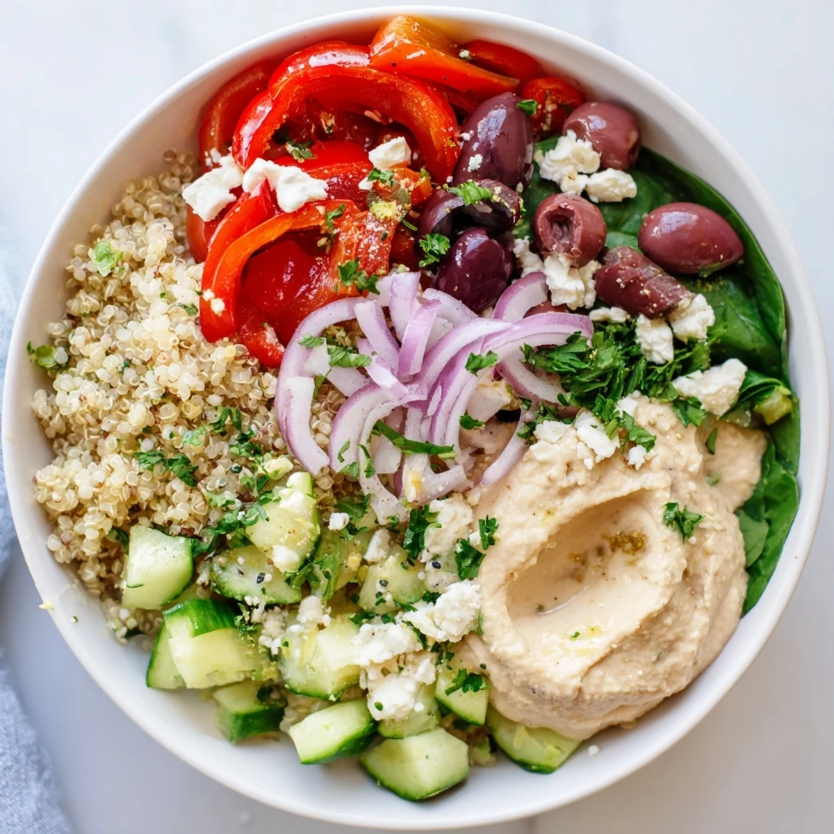 Fluffy Mediterranean Quinoa Bowl with Hummus drizzled with lemon-tahini dressing and garnished with parsley.