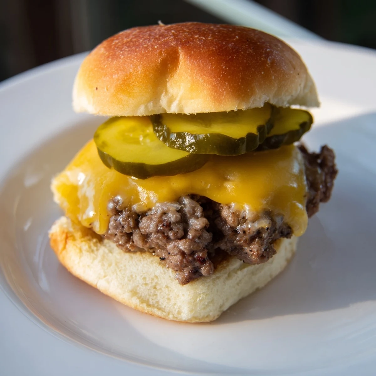 Golden-brown beef sliders with melted cheddar and tangy pickles on toasted buns, ready to serve at a party.