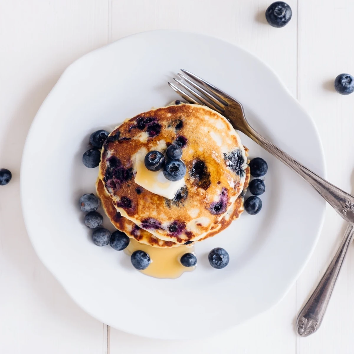 Golden Fluffy Greek Yogurt Blueberry Pancakes cooking on a skillet with bubbling batter.