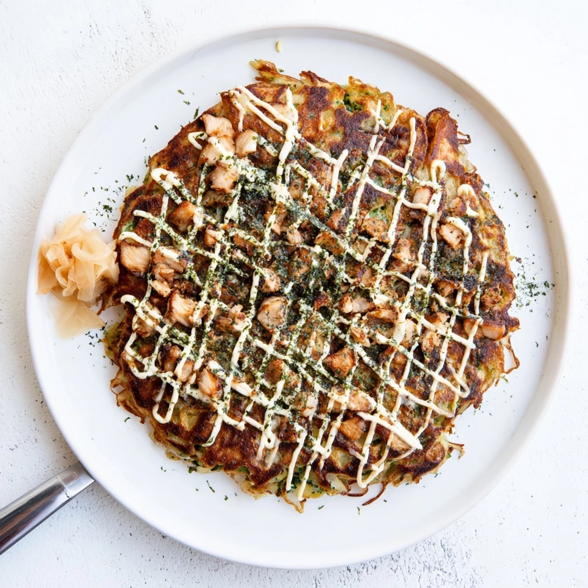 Sizzling Chicken Okonomiyaki on a griddle, featuring a savory pancake filled with cabbage and chicken, ready to serve.