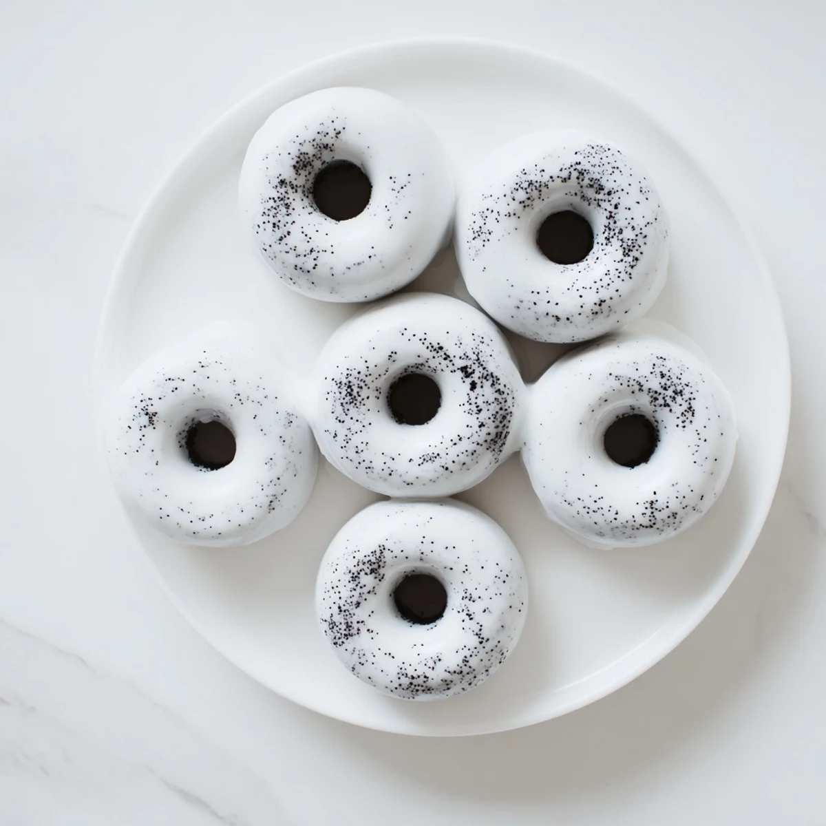 Twelve mini Black Sesame Mochi Donuts rest on a wire rack after baking, showcasing their round shape and textured surface.