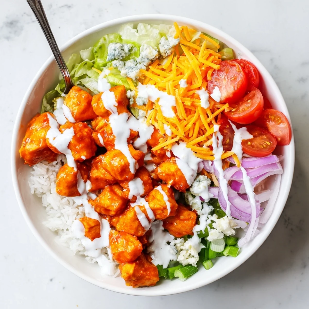 Buffalo Chicken Bowls showcase golden chicken tossed in tangy hot sauce over rice with fresh toppings and a cool ranch swirl.