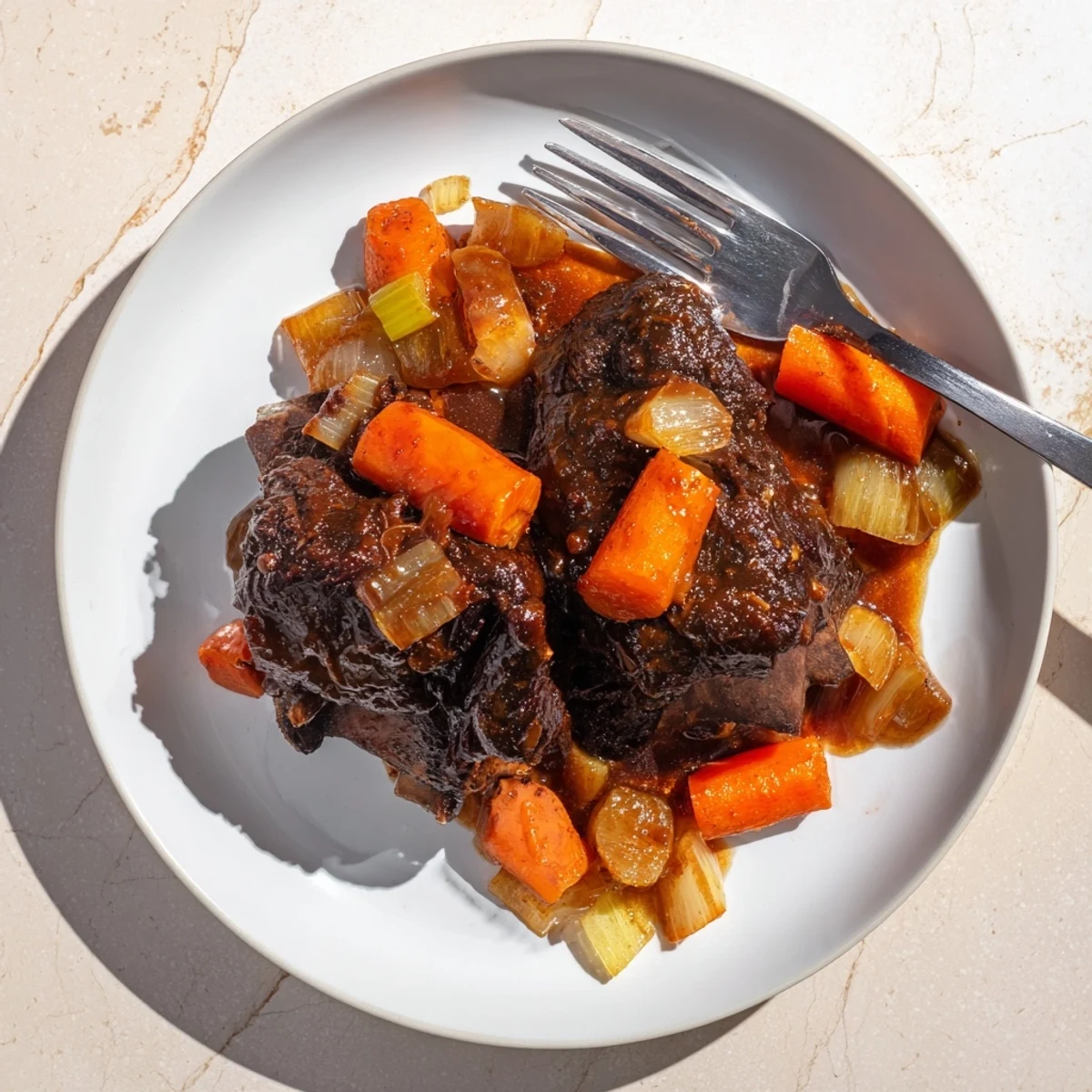 Glossy maple bourbon glazed short ribs resting on a white plate with rich caramelized sauce drizzled over the tender meat