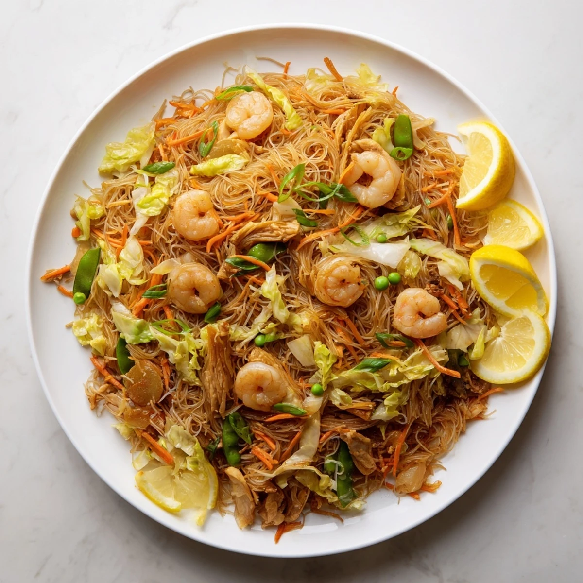 Golden mound of savory pancit bihon stir-fried with tender chicken, shrimp, and colorful julienned vegetables in a rich soy-based sauce