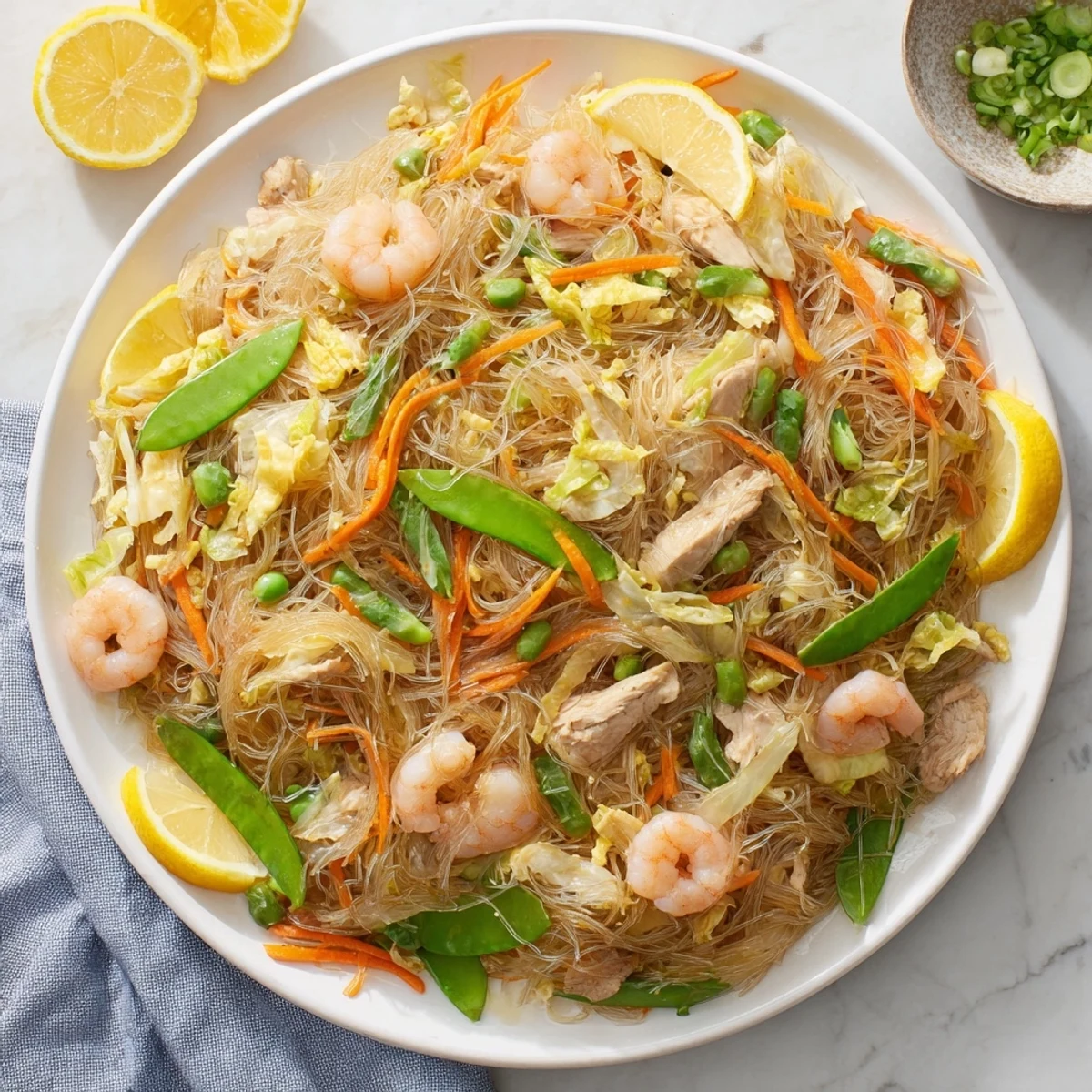 Steaming plate of traditional pancit bihon noodles tossed with crisp cabbage, carrots, and succulent seafood garnished with fresh scallions