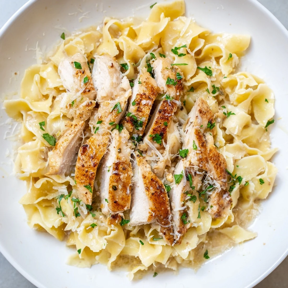 Tender seasoned chicken served over silky egg noodles with melted butter and parmesan in one pan