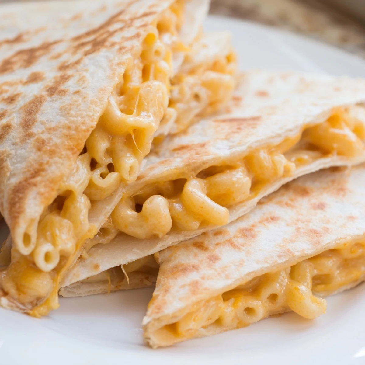 Golden brown mac and cheese quesadilla cut into wedges revealing creamy cheese filling