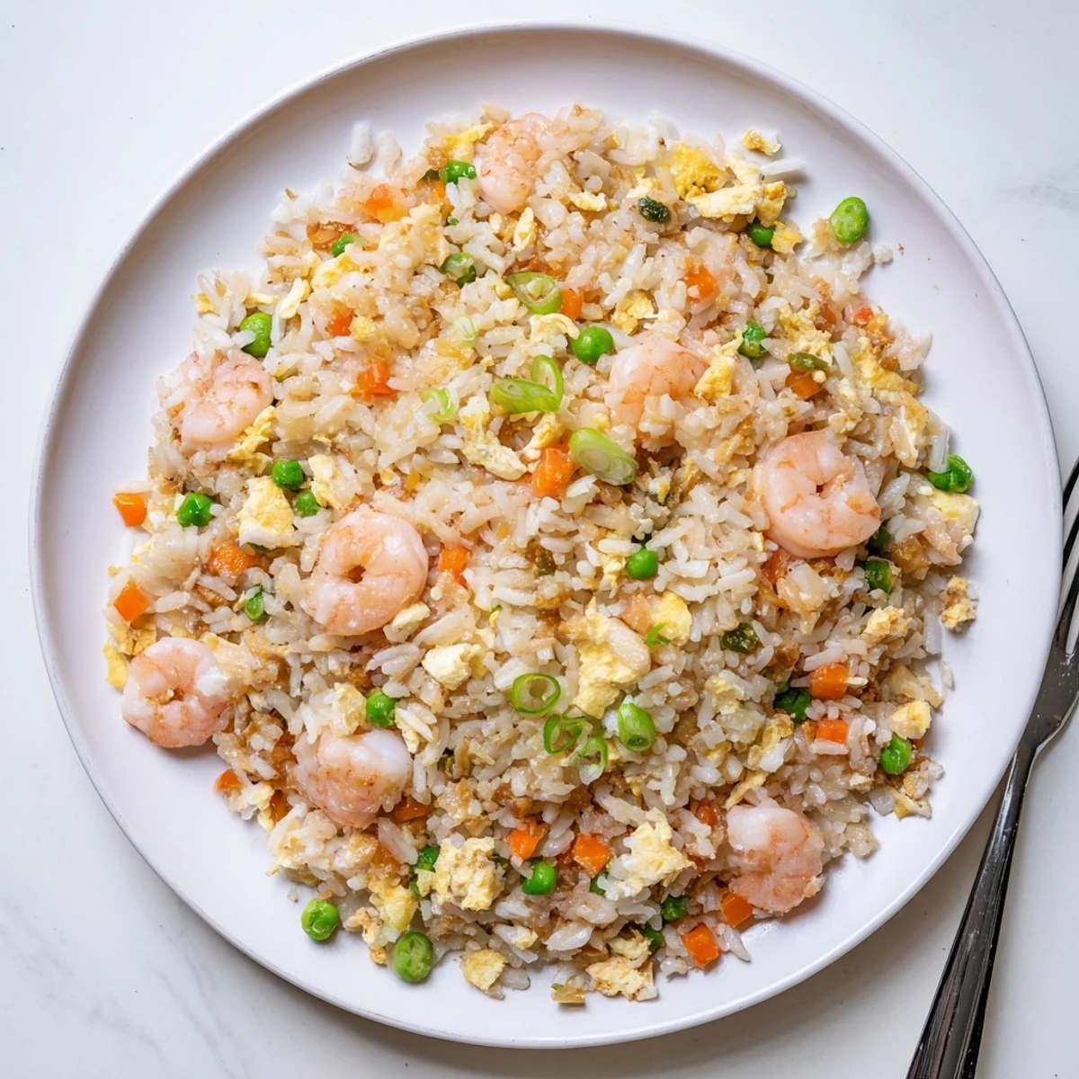 Close-up steaming bowl of authentic shrimp fried rice garnished with fresh scallions and tender pea carrots
