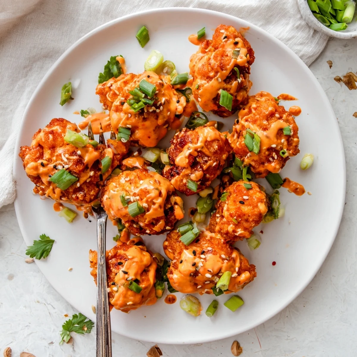 Plate of Spicy Bang Bang Chicken drizzled with spicy mayo sauce and topped with sesame seeds