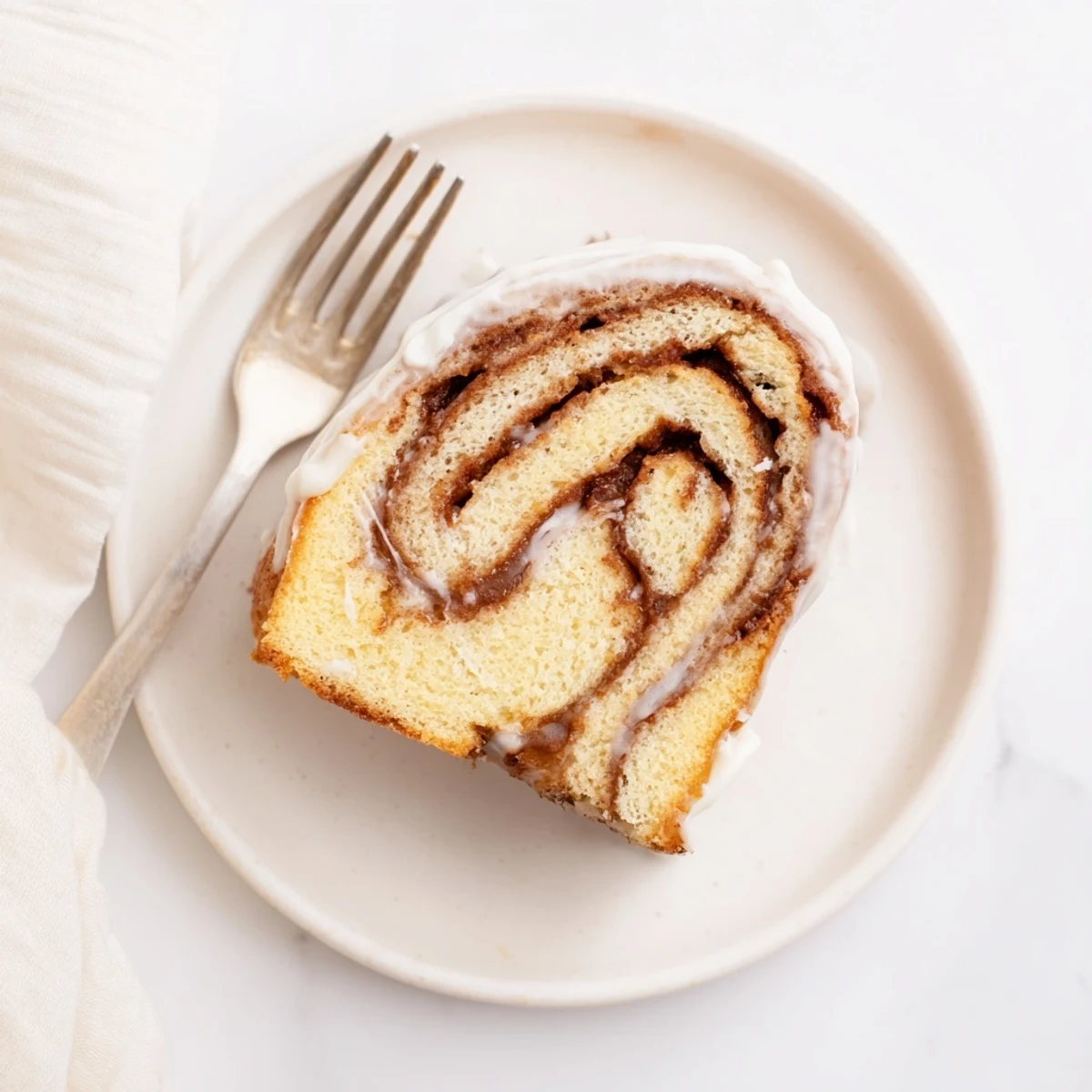 Golden swirled cinnamon roll cake with ribbons of brown sugar cinnamon glaze dripping down the sides