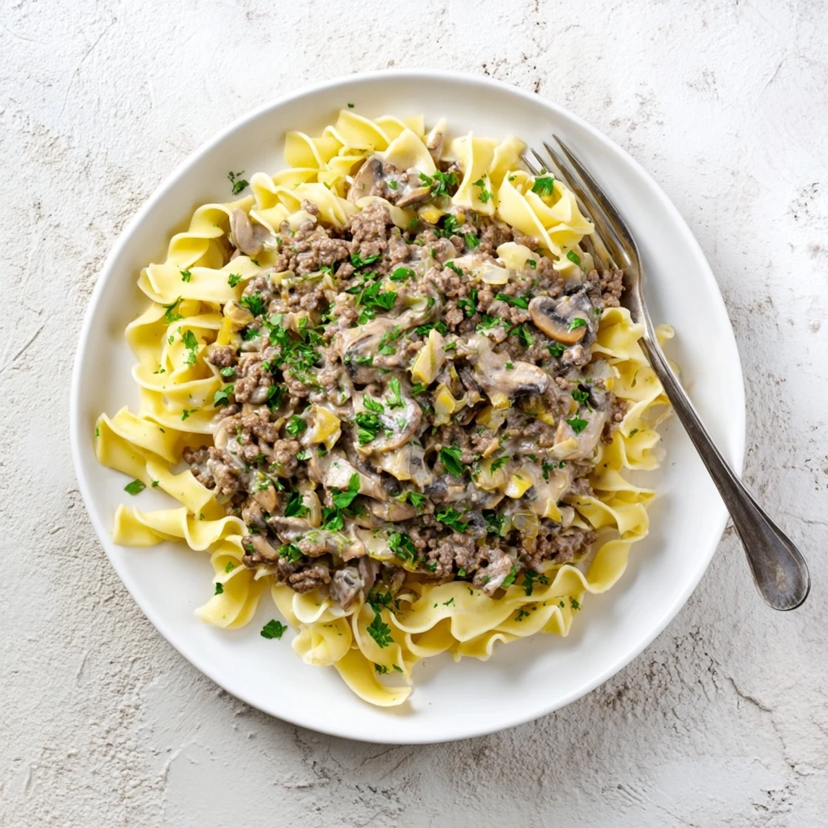 Hearty hamburger stroganoff featuring rich sour cream sauce atop a bed of wide noodles