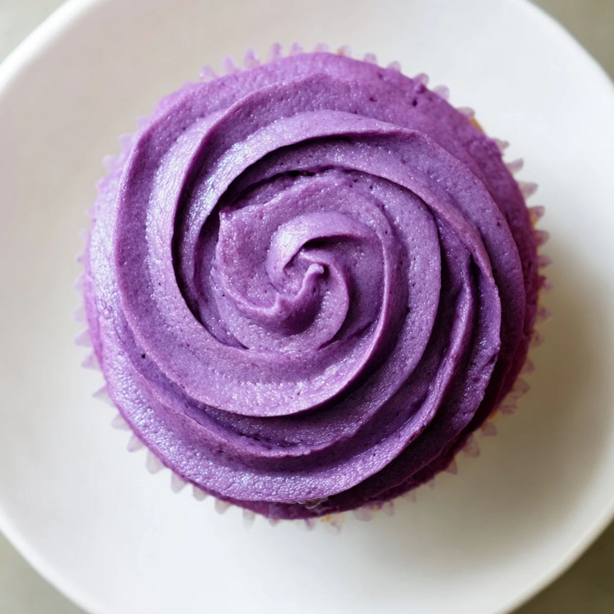 Purple frosted grape soda cupcakes on a white plate topped with colorful sprinkles