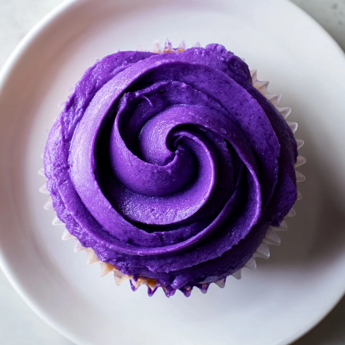 Fluffy grape soda cupcakes with swirls of purple buttercream frosting on a cooling rack