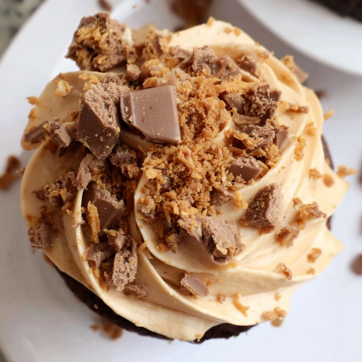 Decadent Butterfinger cupcakes topped with peanut butter frosting and crushed candy bar pieces