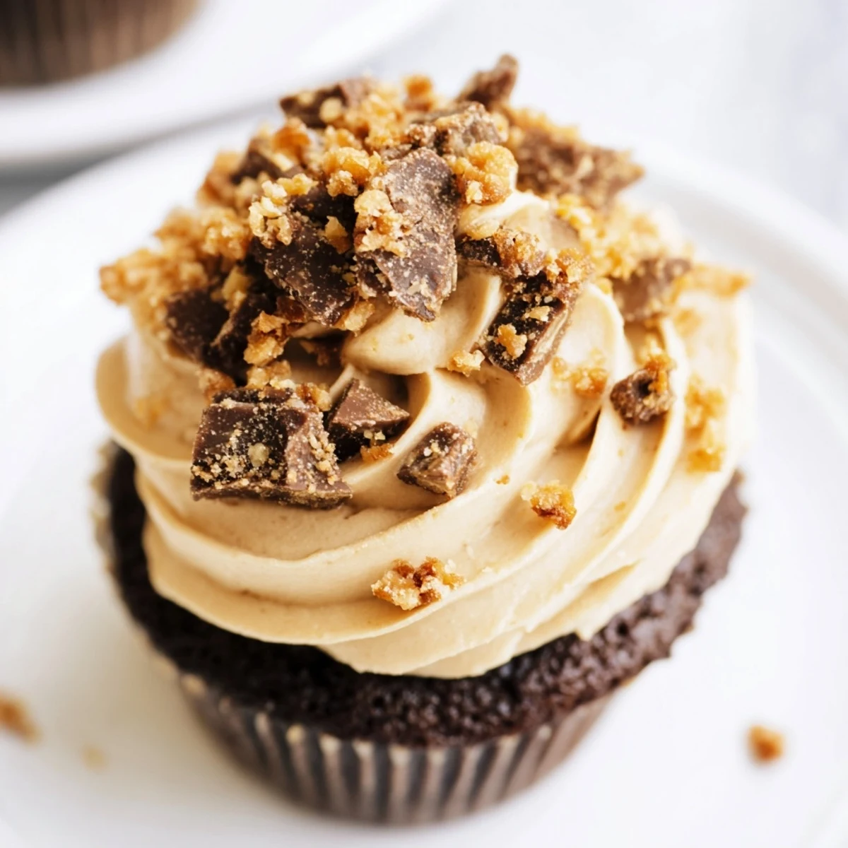 Chocolate peanut butter cupcakes piped with Butterfinger frosting and crunchy candy topping