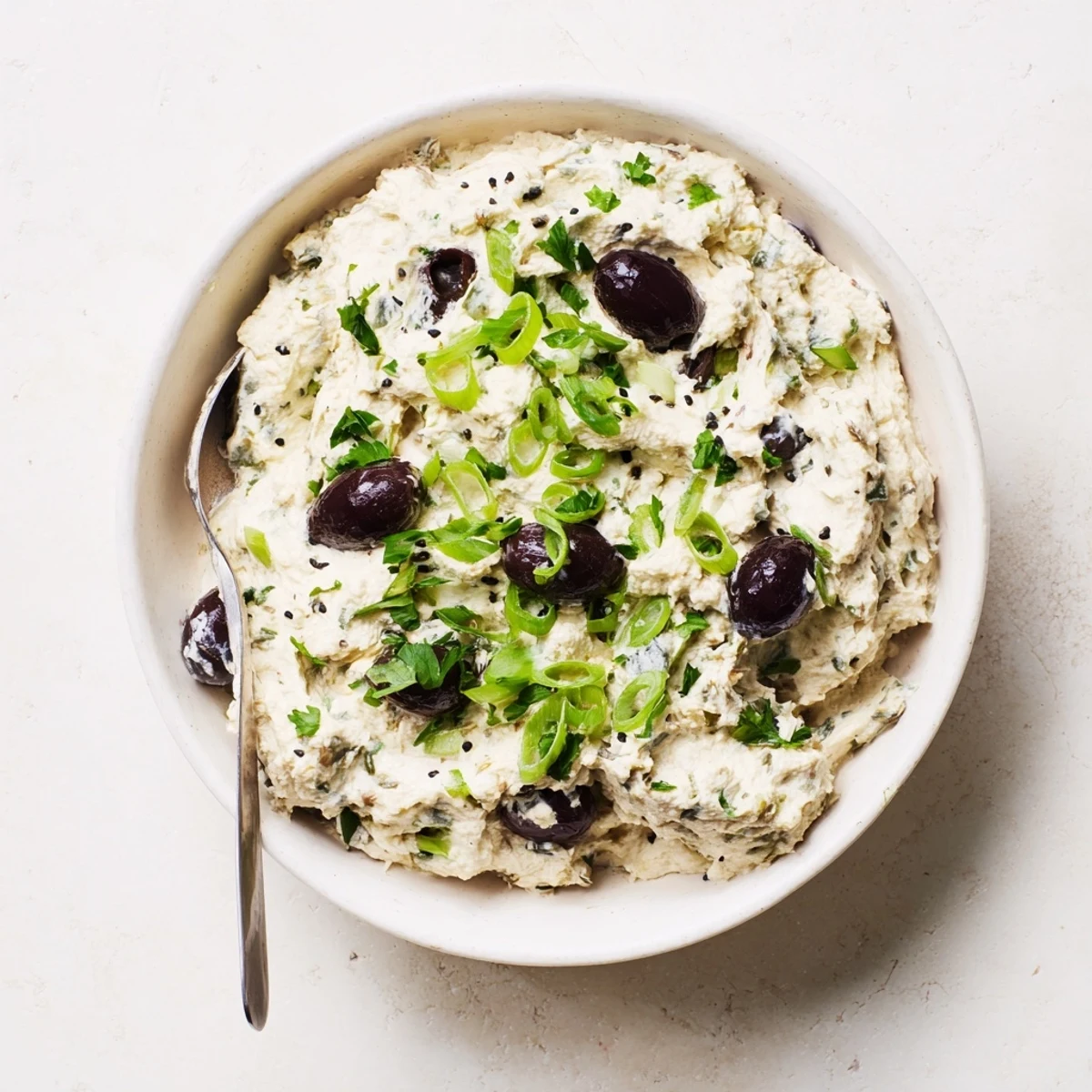 Tangy cream cheese dip with briny olives and green onions on a party platter