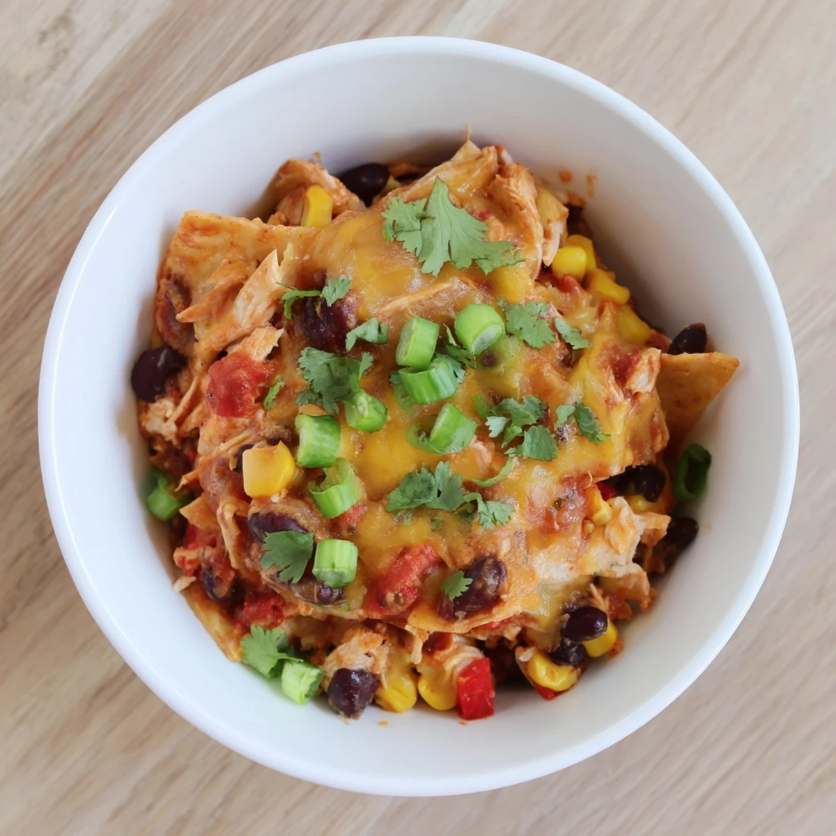 Slow cooker chicken enchilada casserole bubbling with melted cheese and colorful layered vegetables