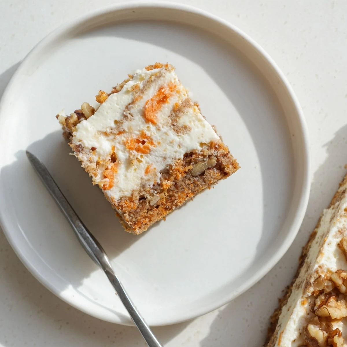 Slice of carrot cake cream cheese bar displaying the swirled vanilla and spiced cake layers with crumbly edges