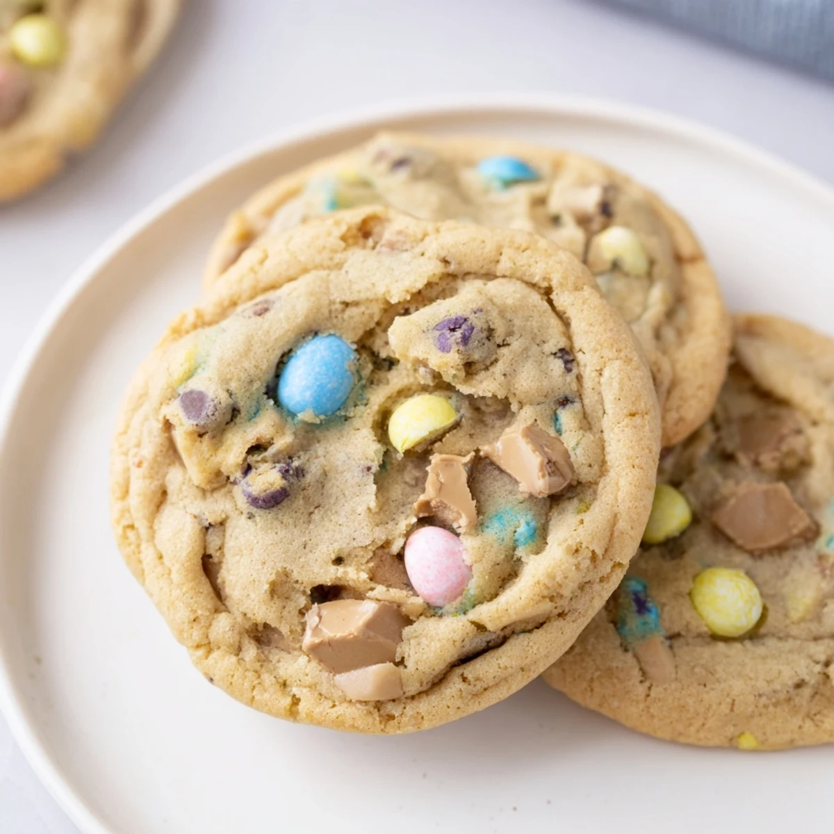 Soft Cadbury Egg Cookies with colorful candy pieces and melty chocolate chips on a rustic baking sheet