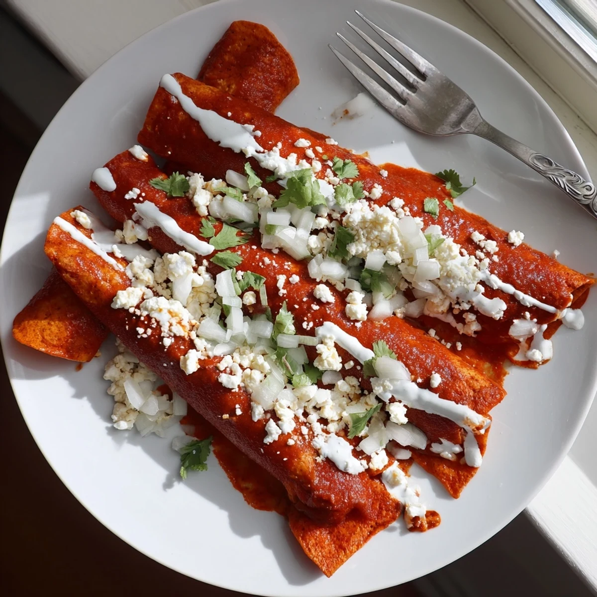 Golden entomatadas draped in rich tomato sauce topped with crumbled queso fresco and fresh cilantro