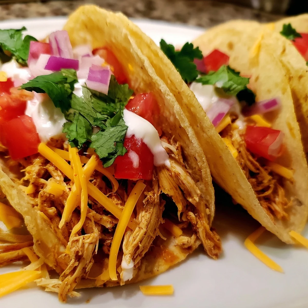 Juicy slow cooker shredded chicken tacos topped with fresh lettuce, tomatoes, and melted cheese