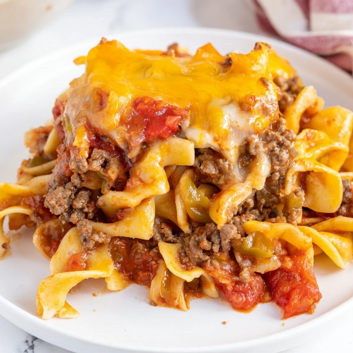 Beef Noodle Casserole bubbling with melted cheddar, golden edges, parsley garnish.
