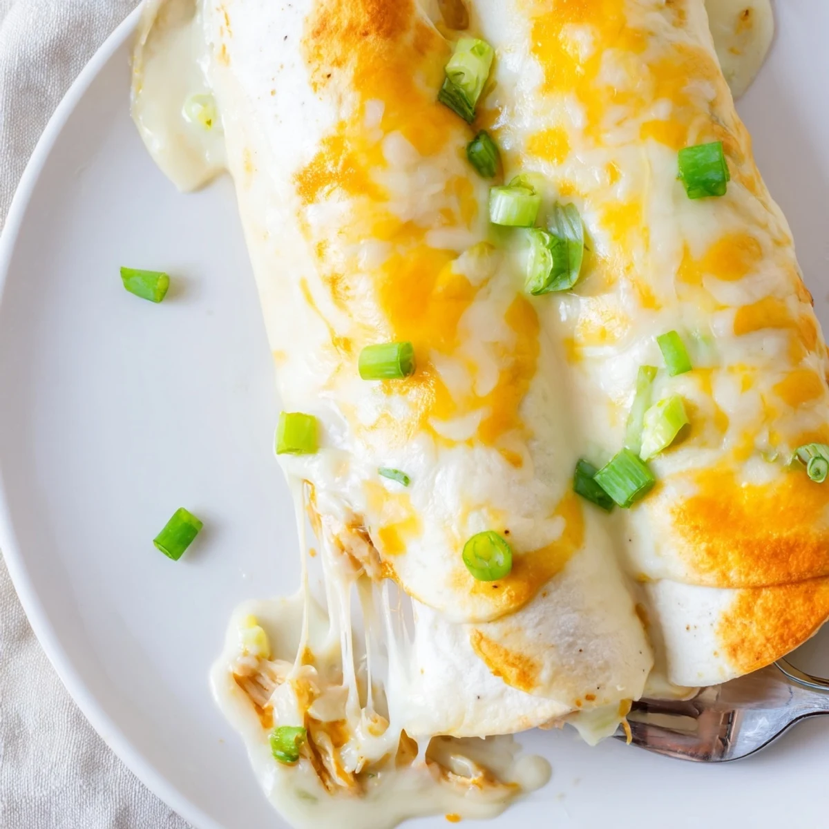 Creamy White Chicken Enchiladas bubbling golden, topped with cilantro and sliced green onions