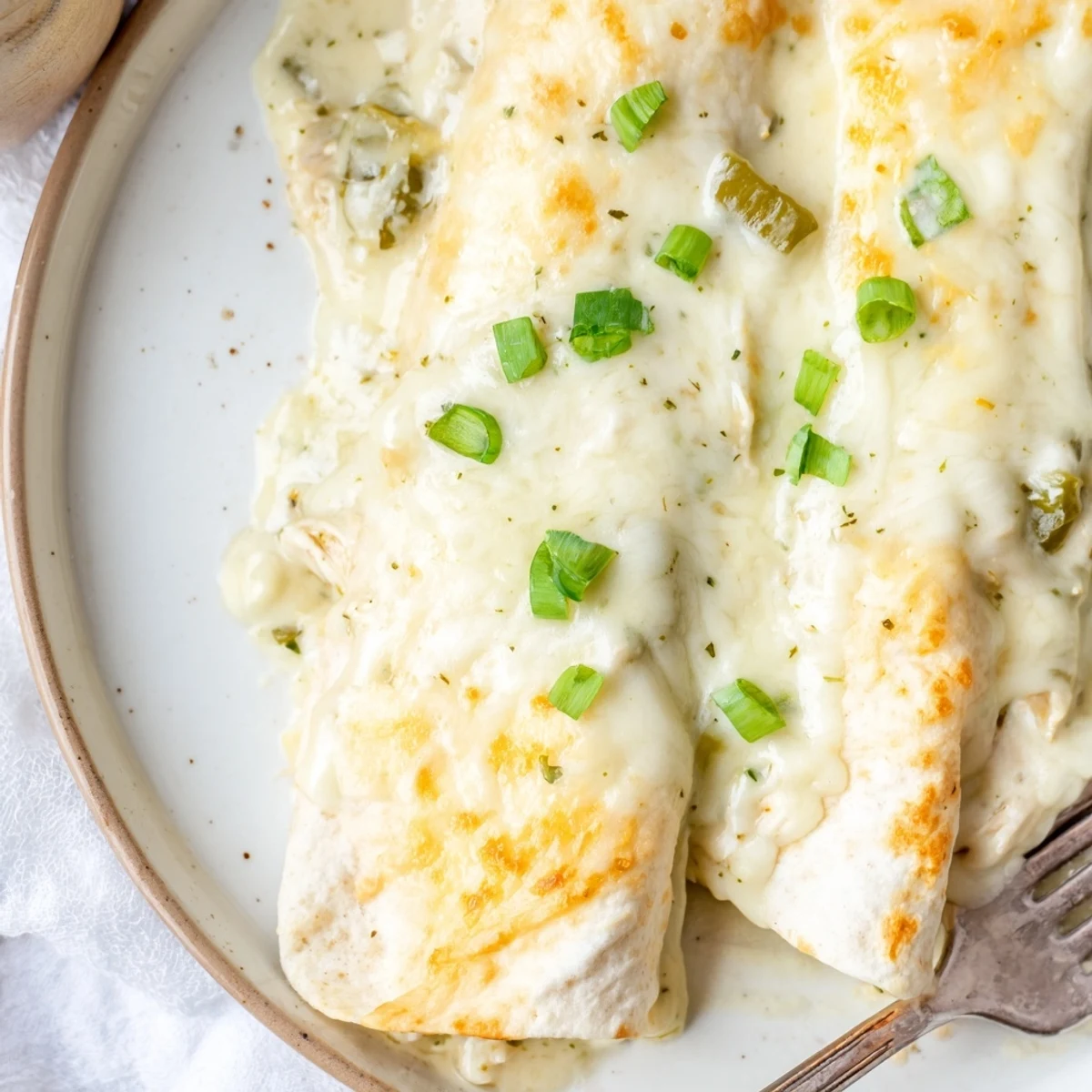 Baked Creamy White Chicken Enchiladas served with Spanish rice, creamy sauce dripping