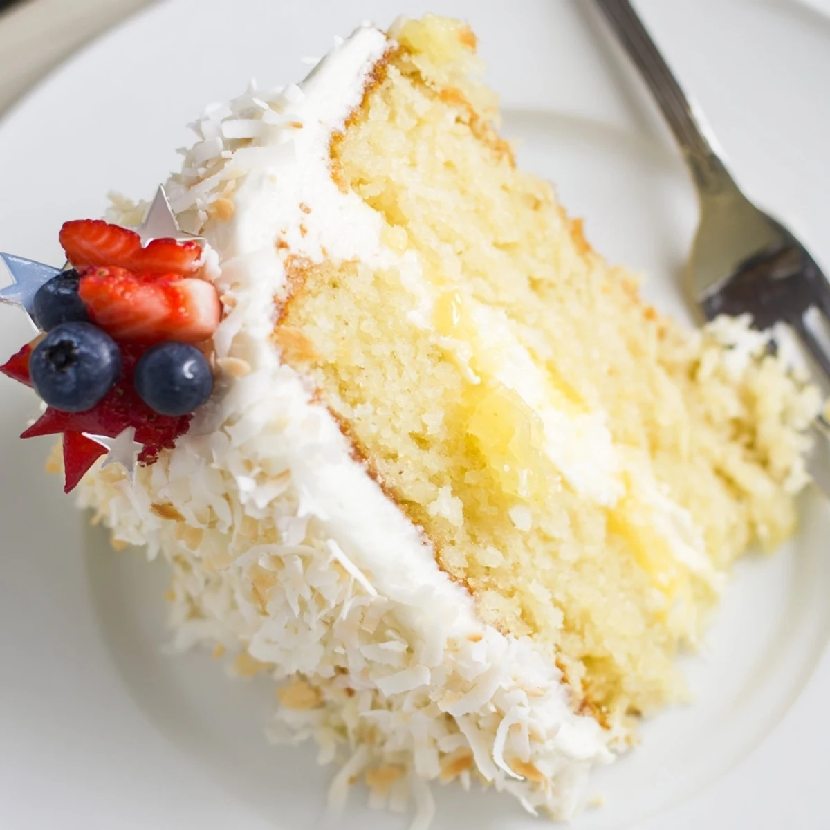 Sliced Pineapple Coconut God Bless America Cake on platter, cream cheese frosting.