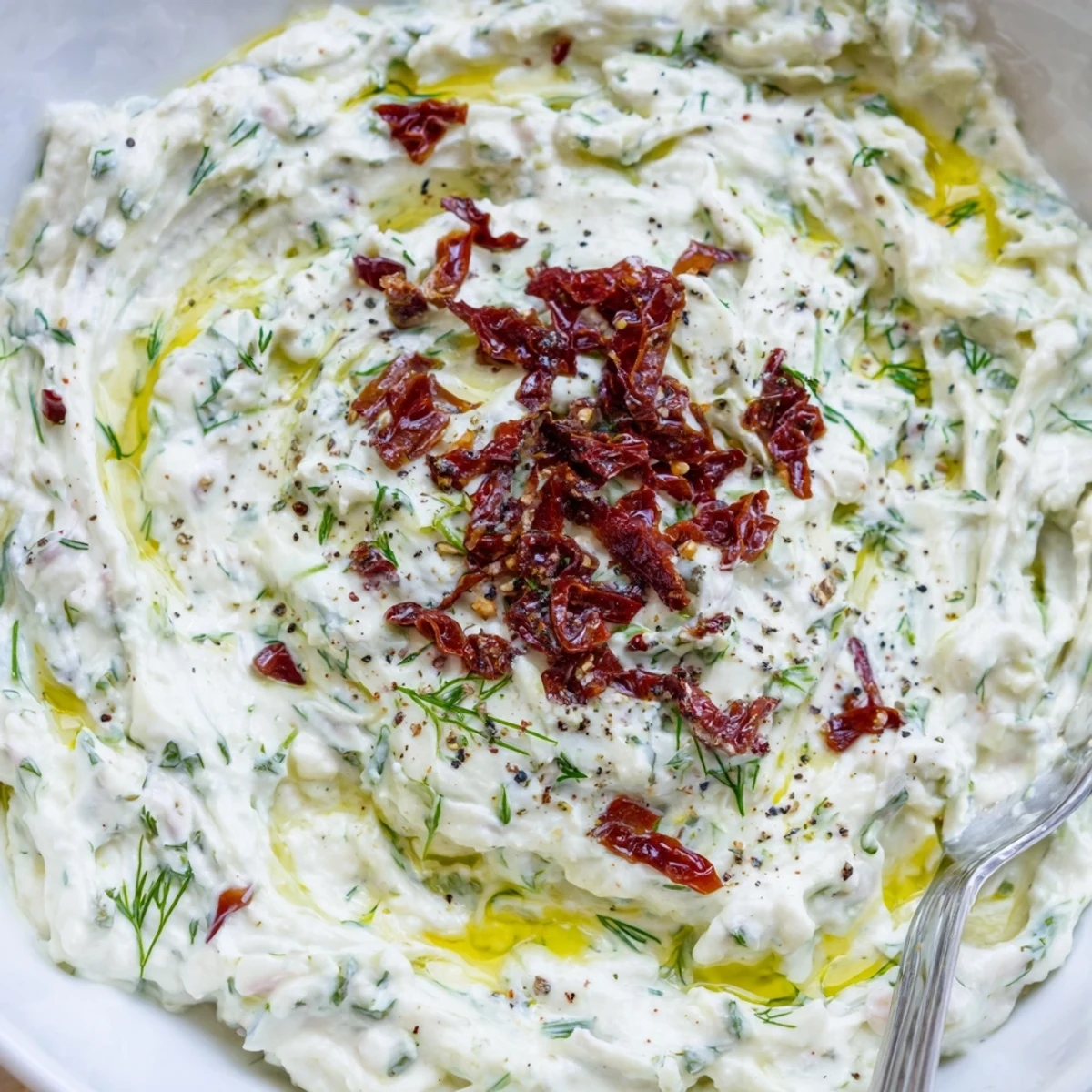 Creamy Sun Dried Tomato Tzatziki chilled in bowl, garnished with olive oil