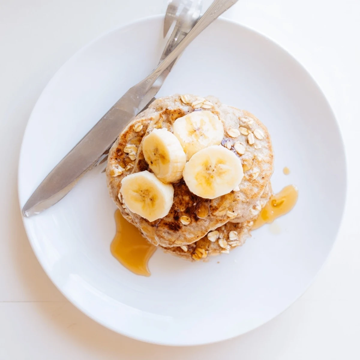 Fluffy protein banana pancakes served with walnuts and honey drizzle on a rustic wooden breakfast table