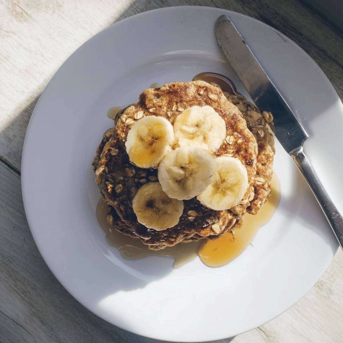 Healthy protein banana pancakes cooking in a skillet with bubbles forming on the golden brown surface