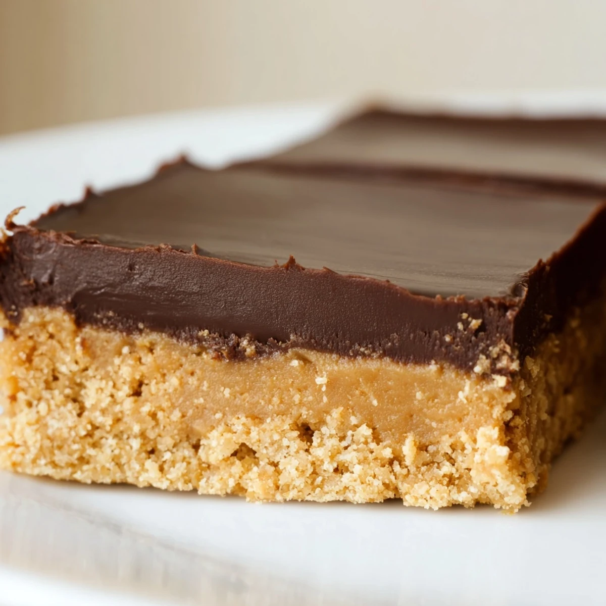 Rich chocolate-topped peanut butter bars arranged on a serving platter, showcasing creamy layers and square cuts