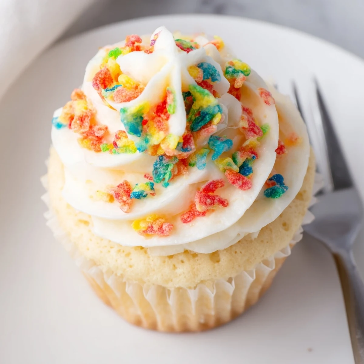 Bright, creamy Fruity Pebbles Cereal Frosting piped onto vanilla cupcakes, colorful crunch