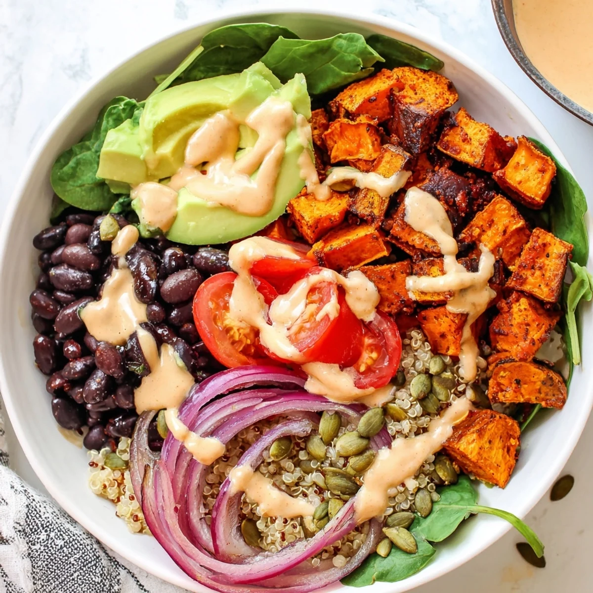 Smoky sweet potato bowl served over fluffy quinoa with zesty lemon tahini sauce