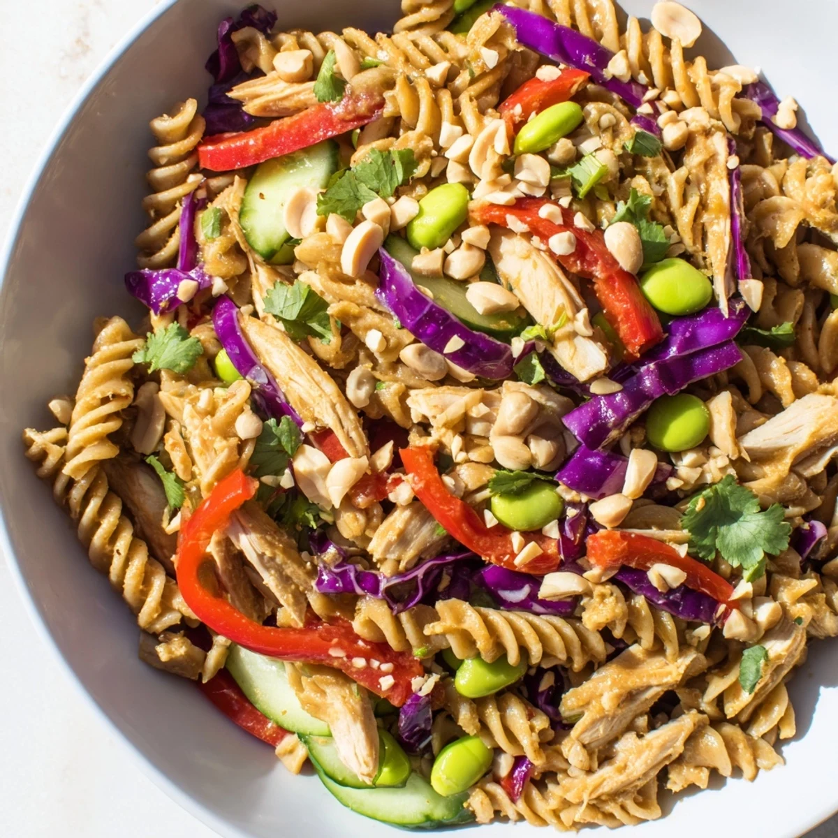 Grilled chicken and edamame top this protein packed Thai pasta salad in a bowl