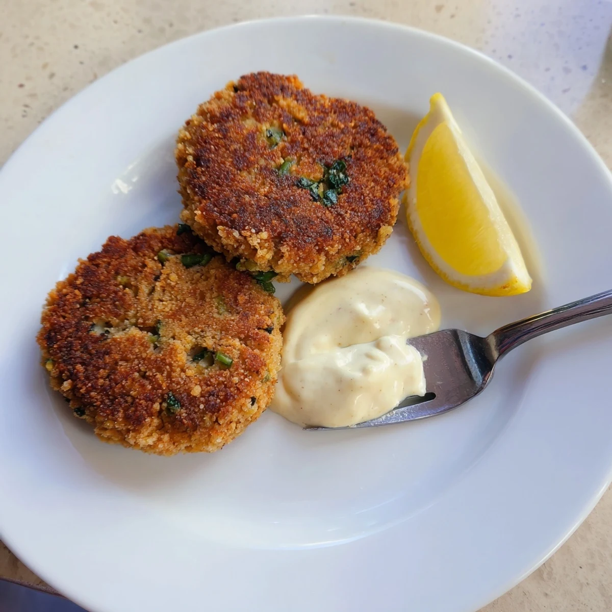 Warm lemon garlic Alaska salmon cakes resting on a plate beside bright citrus aioli