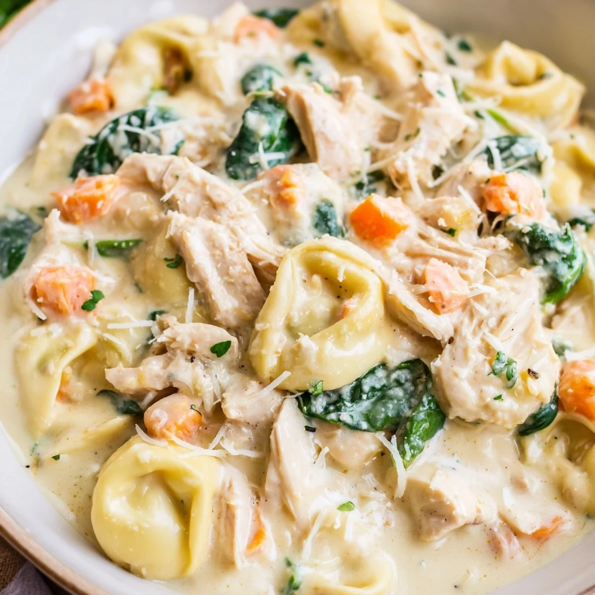 Hearty crockpot chicken tortellini topped with Parmesan cheese in a white bowl