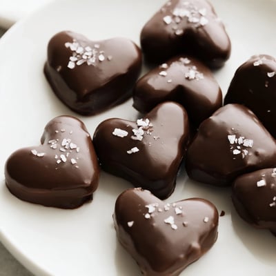 Chocolate Peanut Butter Hearts with Sea Salt stacked on a white plate, ready to serve as a sweet and salty dessert treat.