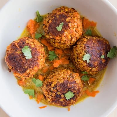 Warm Carrot And Chickpea Balls In Coconut Curry Sauce ladled over rice